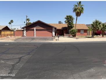 Charming single-story home featuring a two car garage, desert landscaping, and mature palm trees at 8609 S 16Th St, Phoenix, AZ 85042