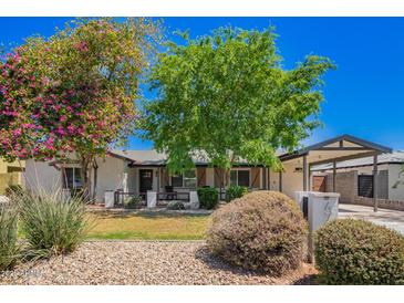 Charming home with mature trees, a well-manicured lawn, and a convenient covered carport at 6741 N 10Th St, Phoenix, AZ 85014