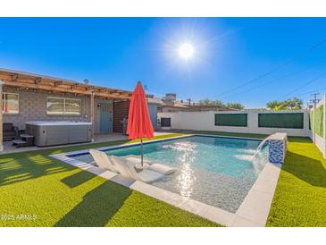 Stunning pool featuring a modern water feature, in-water lounge chairs and vibrant artificial turf at 8522 E Virginia Ave, Scottsdale, AZ 85257