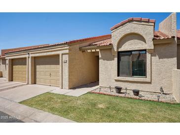 Stucco exterior with well-kept lawn, two-car garage, and terracotta tiled roof in a residential area at 1021 S Greenfield Rd # 1077, Mesa, AZ 85206