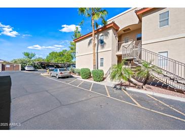 Condo exterior featuring tan stucco, desert landscaping, parking, and entry stairs at 10410 N Cave Creek Rd # 1100, Phoenix, AZ 85020
