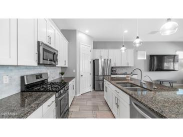 Updated kitchen features granite countertops, stainless steel appliances, and white cabinets at 1104 E Tekoa Ave, Gilbert, AZ 85298