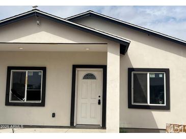 Charming home featuring a white front door, dark framed windows and a security camera at 1519 N Etta St, Casa Grande, AZ 85122