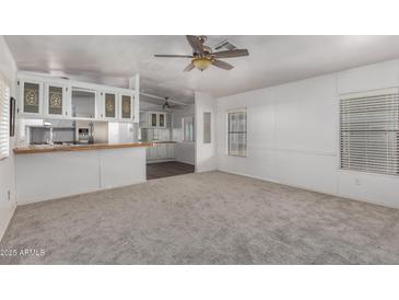 Sun-filled living room featuring neutral carpet, light walls, and open floorplan at 201 S Greenfield Rd # 129, Mesa, AZ 85206