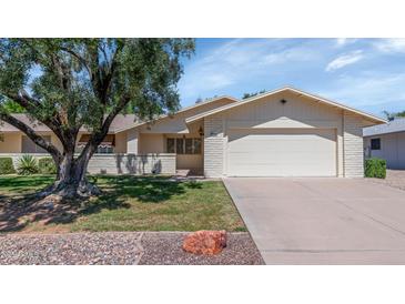 Charming single-story home with a well-manicured lawn and mature tree in a tranquil neighborhood at 21222 N Aurora Dr, Sun City West, AZ 85375