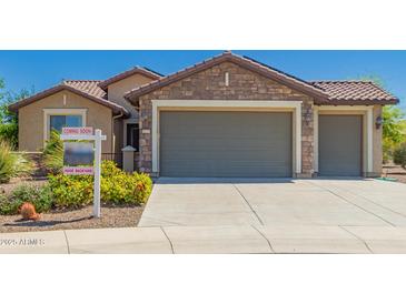 Charming single-Gathering home featuring stone accents and a three-car garage, landscaped with desert plants at 26270 W Horsham Ct, Buckeye, AZ 85396
