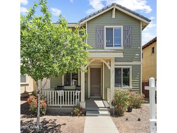 Charming two-story home with a cozy front porch, green siding, and well-maintained landscaping at 2941 N Evergreen St, Buckeye, AZ 85396