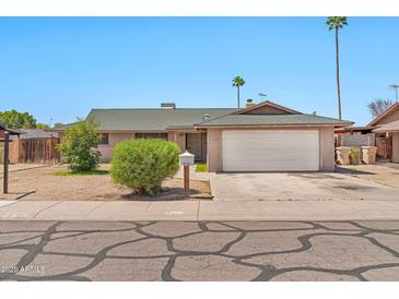 Ranch-style home with two-car garage, desert landscaping, and inviting curb appeal under a clear blue sky at 9102 N 56Th Ln, Glendale, AZ 85302