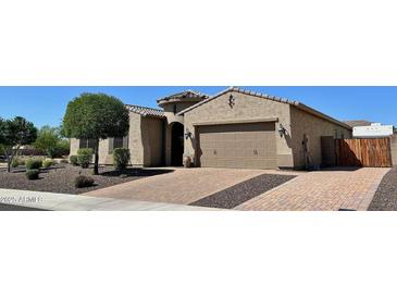 Charming single-Gathering home featuring a two-car garage, neutral stucco exterior, and brick-paved driveway at 9390 W Louise Dr, Peoria, AZ 85383