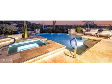 Inviting pool and spa area with stone tile, complete with handrails for easy access and relaxing ambiance at 36075 N Summit Dr, Cave Creek, AZ 85331