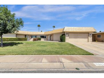 Charming single-story home with a well-maintained lawn, desert landscaping, and attached garage at 10502 W Hutton Dr, Sun City, AZ 85351