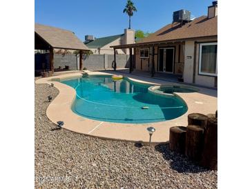 Backyard swimming pool with a hot tub, rock landscaping, and covered patio offers a great space for outdoor entertaining at 12512 N 85Th Ave, Peoria, AZ 85381