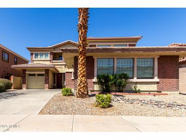 Two-story home featuring a 2-car garage, brick accents, and a well-maintained front yard with desert landscaping at 16022 W Desert Mirage Dr, Surprise, AZ 85379