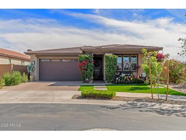 Charming home featuring a well-manicured lawn, mature shrubs, and a brick-paved driveway leading to a two-car garage at 20839 E Kingbird Dr, Queen Creek, AZ 85142