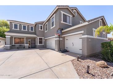 Spacious home showcasing a three-car garage and inviting front porch, perfect for suburban living at 21147 E Via Del Oro --, Queen Creek, AZ 85142