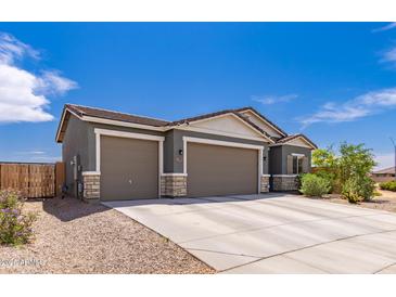 Charming home featuring a three-car garage, neutral paint and desert landscaping at 2458 N Abbey Rd, Casa Grande, AZ 85122