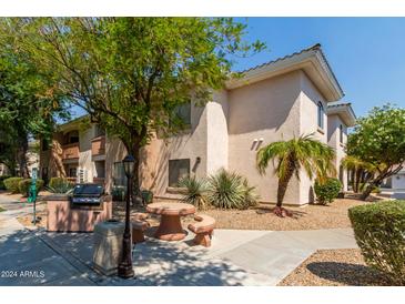 Inviting condo featuring outdoor grilling and seating area surrounded by mature landscaping at 10030 W Indian School Rd # 221, Phoenix, AZ 85037
