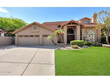 Charming home featuring a three-car garage, tile roof, lush green lawn, and desert landscaping at 14034 S 34Th Pl, Phoenix, AZ 85044