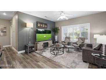 Comfortable living room boasts a ceiling fan, plantation shutters, and entertainment center with fireplace at 16246 W Talara Way, Surprise, AZ 85374