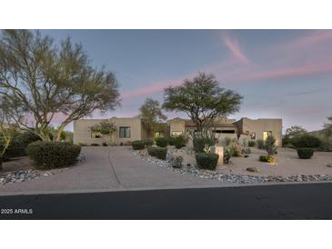 Stunning desert home featuring mature landscaping, gravel driveway, and ample curb appeal at twilight at 26049 N 104Th Pl, Scottsdale, AZ 85255