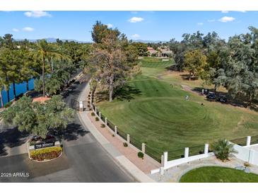 Scenic view of a golf course and community entrance with lush landscaping and a lake at 3671 S Greythorne Way, Chandler, AZ 85248