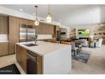 Open kitchen featuring a white island, stainless steel appliances, with seamless flow into the dining and living areas at 5533 E Stella Ln, Paradise Valley, AZ 85253