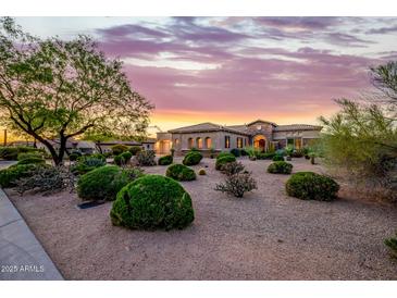 Desert landscaping surrounds a stunning home beneath a vibrant sunset sky at 10934 E La Verna Way, Scottsdale, AZ 85262