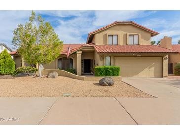 Tan two story home with a tile roof, gravel front yard, and an attached two car garage at 6019 E Paradise Ln, Scottsdale, AZ 85254