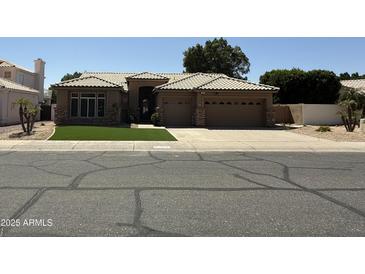 Charming single-story home featuring a tile roof, a three-car garage, and manicured front lawn at 6821 W Donald Dr, Glendale, AZ 85310