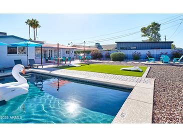 Inviting pool area featuring lounge chairs, patio dining, and artificial turf cornhole in a beautifully landscaped backyard at 8444 E Piccadilly Rd, Scottsdale, AZ 85251