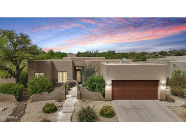 A lovely single-story home featuring a stucco exterior, desert landscaping, and a cozy two-car garage at dusk at 11366 E White Feather Ln, Scottsdale, AZ 85262
