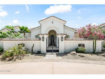 Elegant gated front entrance with desert landscaping and a charming, arched entryway leads to the home's front door at 7003 E Avenida El Alba --, Paradise Valley, AZ 85253