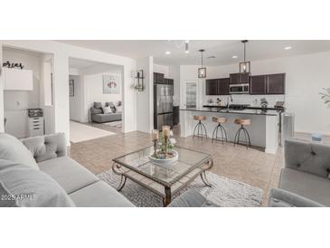 Open-concept living room and kitchen with bar seating, stainless steel appliances, and modern decor at 40192 W Brandt Dr, Maricopa, AZ 85138