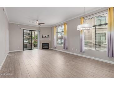 Bright living room featuring a fireplace, ceiling fan, and a sliding door for balcony access at 11640 N Tatum Blvd # 1031, Phoenix, AZ 85028