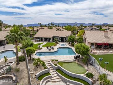 This backyard features a pool, hot tub, putting green, covered patio, and mountain views at 15645 S 17Th St, Phoenix, AZ 85048