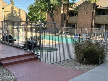 Fenced community pool with clear water, lounge chairs, and grassy area surrounded by residences at 200 E Southern Ave # 133, Tempe, AZ 85282