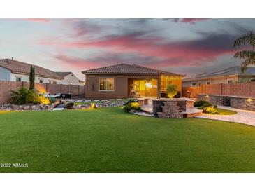 An inviting backyard with a well-manicured lawn, stone fire pit, and ample space for outdoor entertaining at 26065 N 74Th Dr, Peoria, AZ 85383