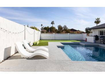 Relaxing backyard featuring a refreshing pool, artificial grass, and lounge chairs at 8132 E Valley View Rd, Scottsdale, AZ 85250