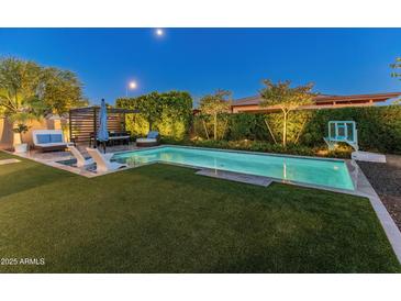 Beautiful backyard with a sparkling pool, lounge area, and lush landscaping, perfect for outdoor entertaining at 11705 W Luxton Ln, Avondale, AZ 85323