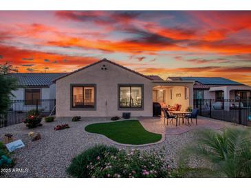 Lush backyard with manicured lawn, an outdoor dining area, and serene landscaping with beautiful sunset at 26915 W Adam Ave, Buckeye, AZ 85396