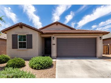 Charming single story home with a two car garage, low maintenance landscaping, and shuttered window accents at 5750 S 250Th Dr, Buckeye, AZ 85326