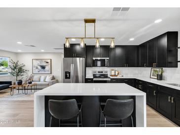 Modern kitchen boasts sleek black cabinets, a white quartz countertop island and stainless appliances at 7149 E Jensen St, Mesa, AZ 85207