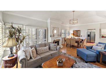 Bright living room featuring hardwood floors, a neutral color palette, fireplace and shuttered windows at 7272 E Gainey Ranch Rd # 48, Scottsdale, AZ 85258