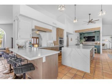 Bright, open kitchen with marble countertops, white cabinets, modern appliances, and terracotta tile flooring at 9736 E Turquoise Ave, Scottsdale, AZ 85258