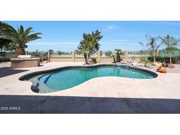 Relaxing backyard pool with custom stone waterfall feature and lush desert landscaping with golf course view at 13458 W Coronado Rd, Goodyear, AZ 85395