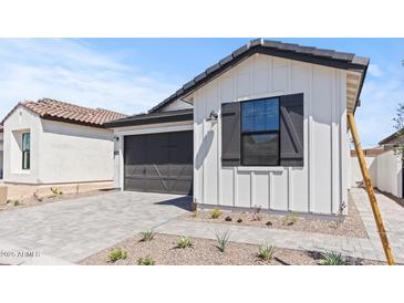 Charming home featuring white siding, a dark gray garage door and meticulous landscaping at 20308 W Roma Ave, Buckeye, AZ 85396
