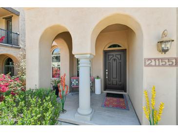Charming front entry with arched columns, cozy seating, and a stylish dark wood door at 21155 W Green St, Buckeye, AZ 85396
