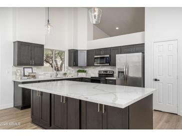Modern kitchen featuring an island with a white countertop and dark cabinets plus stainless steel appliances at 3022 E Emile Zola Ave, Phoenix, AZ 85032