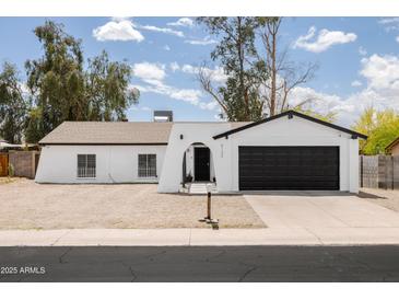 Charming single-story home featuring a crisp white exterior, complemented by a two-car garage and a low maintenance yard at 4133 E Pleasant Ln, Phoenix, AZ 85042