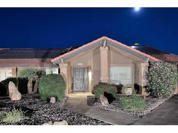 Charming home featuring a tiled roof, solar panels, and a well-manicured front yard at night at 17211 N 58Th St, Scottsdale, AZ 85254